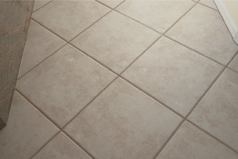 Dirty living room tile floor with stained grout lines before professional cleaning in Port Charlotte Florida